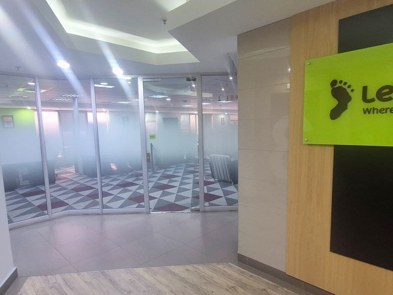 A professional office entrance featuring glass partition walls, modern tiled flooring, and a bright, well-lit reception area with contemporary finishes.