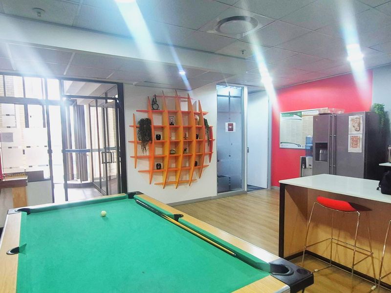 Office break area featuring a pool table, built-in counter, glass partitions, and modern suspended ceiling with recessed lighting.