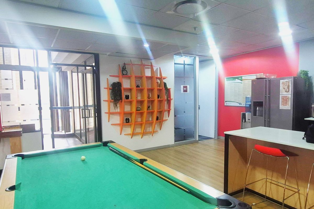 Office break area featuring a pool table, built-in counter, glass partitions, and modern suspended ceiling with recessed lighting.