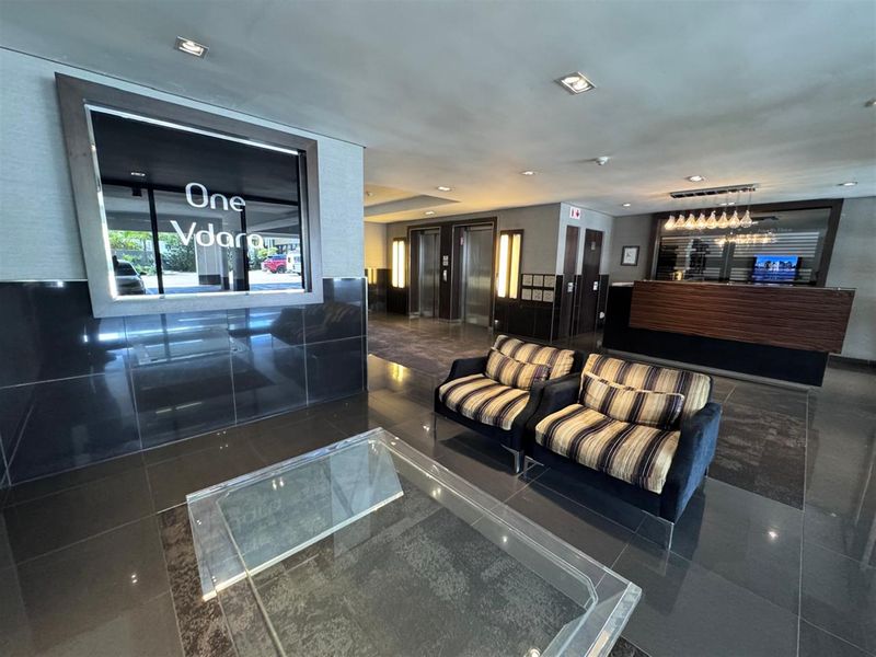 Modern office building lobby featuring a professional reception area, elevator access, and polished tiled flooring with contemporary lighting.