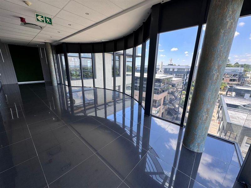 Modern open-plan office space featuring polished tile floors, floor-to-ceiling windows with expansive views, and a contemporary suspended ceiling design.