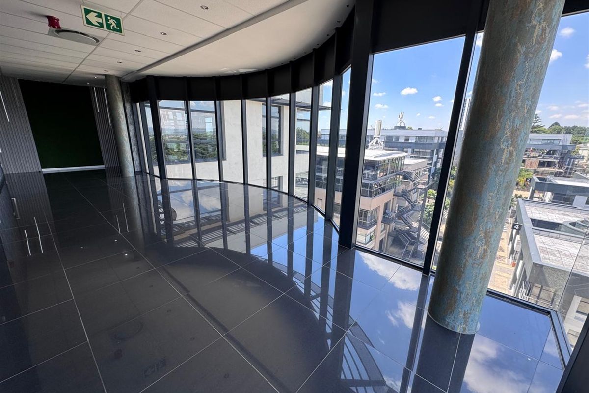 Modern open-plan office space featuring polished tile floors, floor-to-ceiling windows with expansive views, and a contemporary suspended ceiling design.