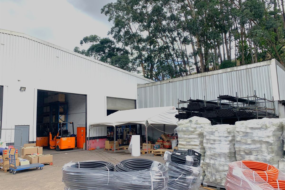 Industrial rear yard area featuring corrugated metal cladding, a large roller shutter door, and concrete hardstand suitable for logistics and storage operations.