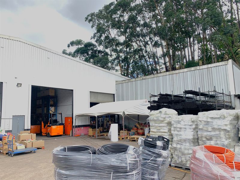 Industrial rear yard area featuring corrugated metal cladding, a large roller shutter door, and concrete hardstand suitable for logistics and storage operations.