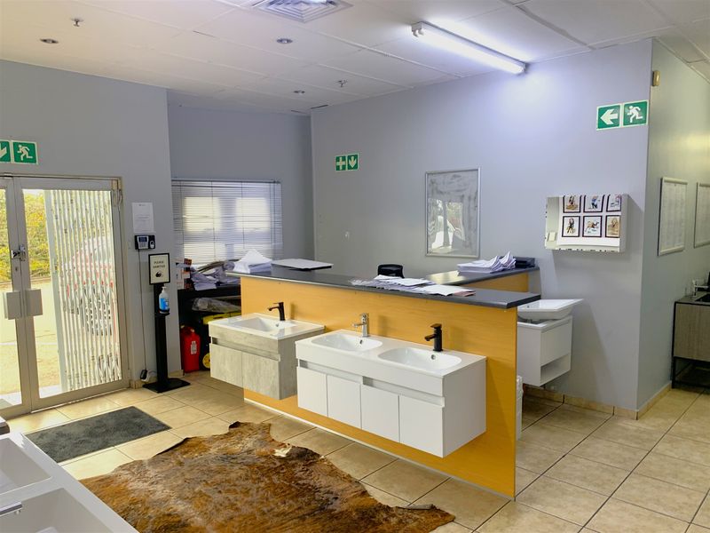 A functional utility or wash area featuring multiple wall-mounted vanity units with integrated basins, tiled flooring, and industrial-style lighting.
