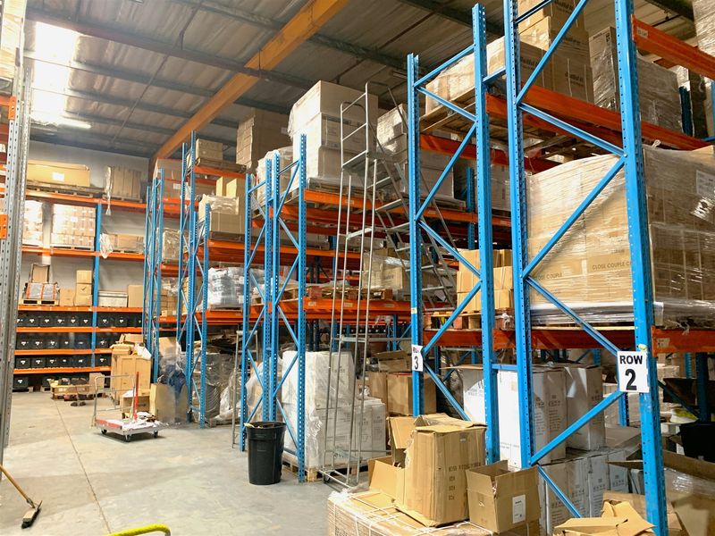 Industrial warehouse space featuring extensive steel pallet racking systems, concrete flooring, and high-clearance ceilings suitable for storage and logistics operations.