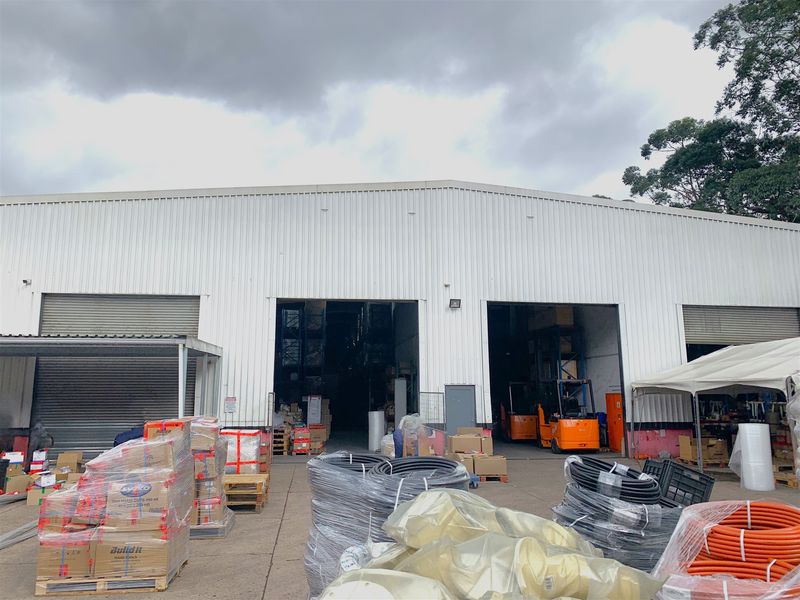 Industrial warehouse exterior featuring large roller shutter access points and corrugated metal cladding, suitable for logistics or storage operations.