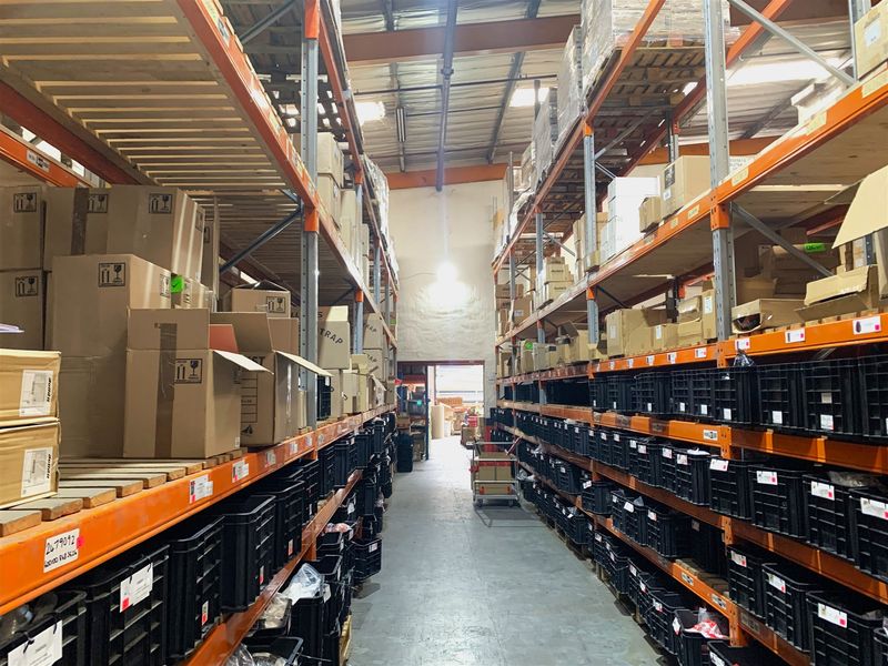 Industrial warehouse space featuring extensive steel racking systems, high ceilings with exposed trusses, and durable concrete flooring, optimized for storage and logistics operations.