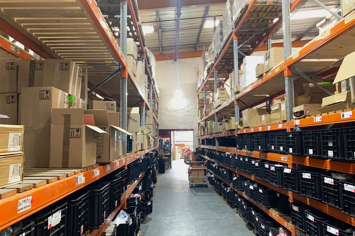 Industrial warehouse space featuring extensive steel racking systems, high ceilings with exposed trusses, and durable concrete flooring, optimized for storage and logistics operations.