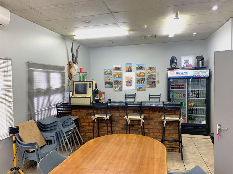 A functional bar area featuring a brick-faced counter, tiled flooring, and drop ceiling, suitable for office or industrial break room use.