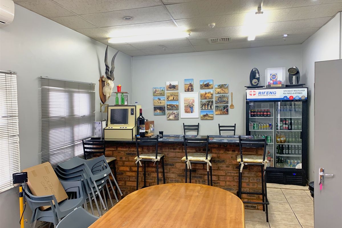 A functional bar area featuring a brick-faced counter, tiled flooring, and drop ceiling, suitable for office or industrial break room use.