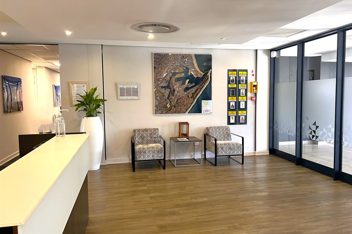 A professional office reception area featuring a reception desk, laminate flooring, and a modern glass partition wall.
