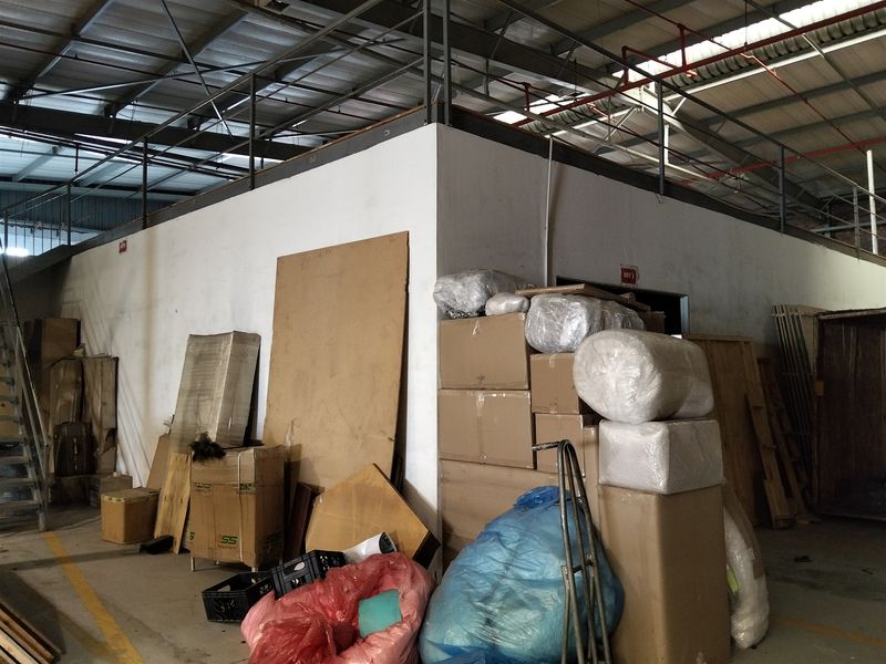 Industrial warehouse space featuring a mezzanine level, exposed steel roof structure, and concrete flooring, suitable for storage or light industrial operations.