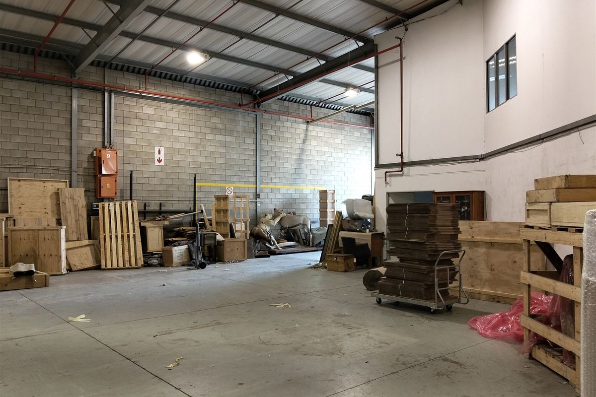 Spacious industrial utility area featuring exposed steel roof trusses, concrete block walls, and durable concrete flooring, suitable for storage or workshop use.