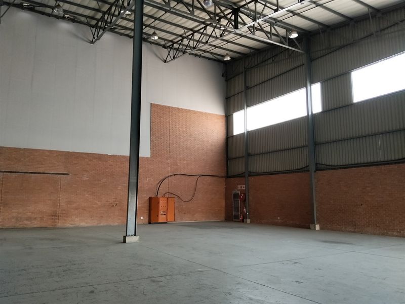 Spacious industrial warehouse unit featuring high ceilings, exposed steel structural elements, durable concrete flooring, and integrated electrical and fire safety infrastructure.