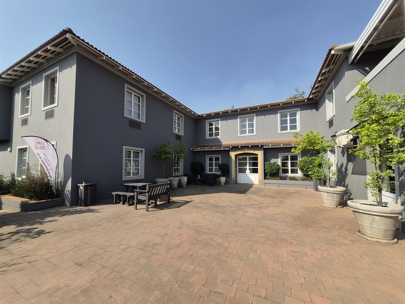 A well-maintained office courtyard featuring terracotta paving, grey exterior walls, and multi-pane windows, providing a professional and accessible outdoor space.