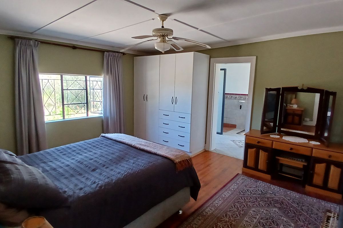 A bedroom featuring timber flooring, a built-in wardrobe, a ceiling fan, and an adjoining bathroom entrance.