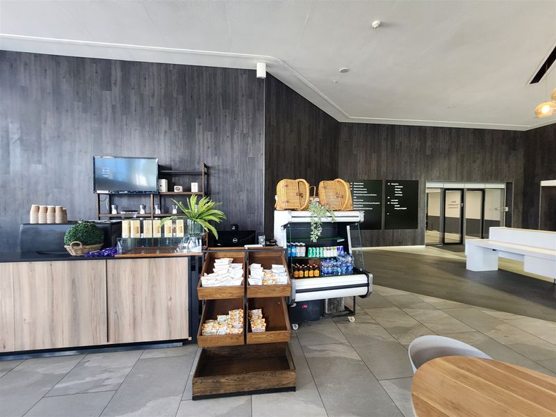 Modern office reception area featuring a built-in service counter, dark wood-look wall paneling, and clear directional signage for building navigation.