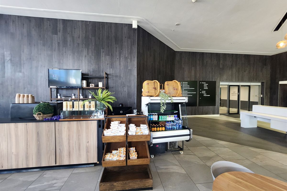 Modern office reception area featuring a built-in service counter, dark wood-look wall paneling, and clear directional signage for building navigation.