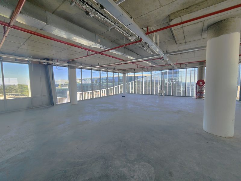 An expansive, open-plan office space featuring floor-to-ceiling windows, exposed industrial-style ceiling services, and concrete flooring, offering a blank canvas for custom fit-outs.