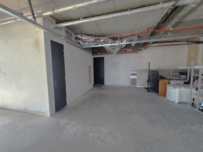 An open-plan office space in shell condition featuring exposed industrial ceilings, ducting, and concrete flooring, ready for custom fit-out.