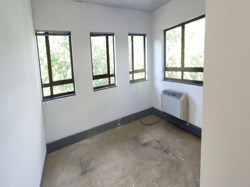 A vacant office space featuring multiple windows, an integrated air conditioning unit, and neutral walls, ready for customization or professional fit-out.