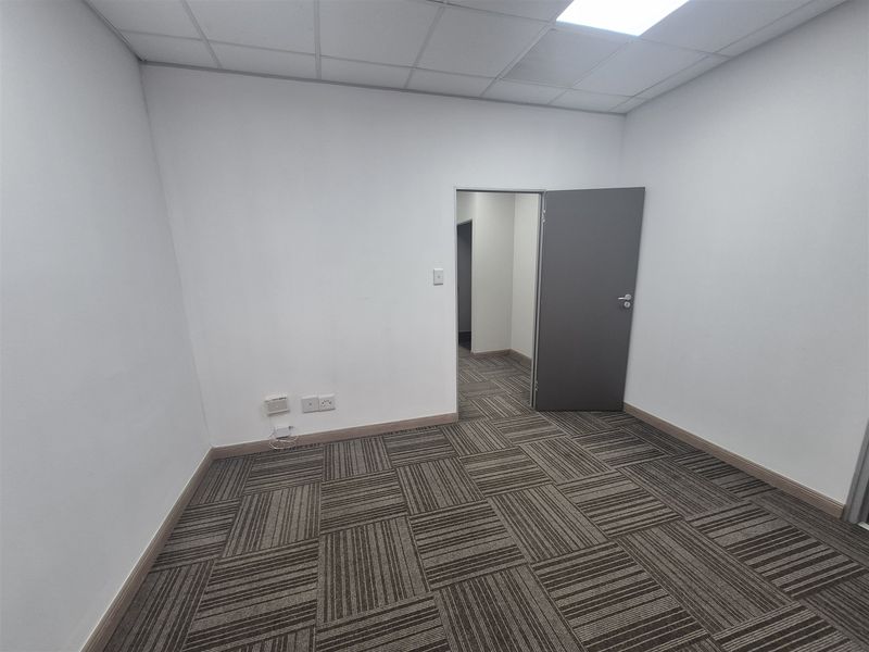 A clean, empty office space featuring neutral carpet tiles, a suspended ceiling with recessed lighting, and integrated electrical and data connectivity.