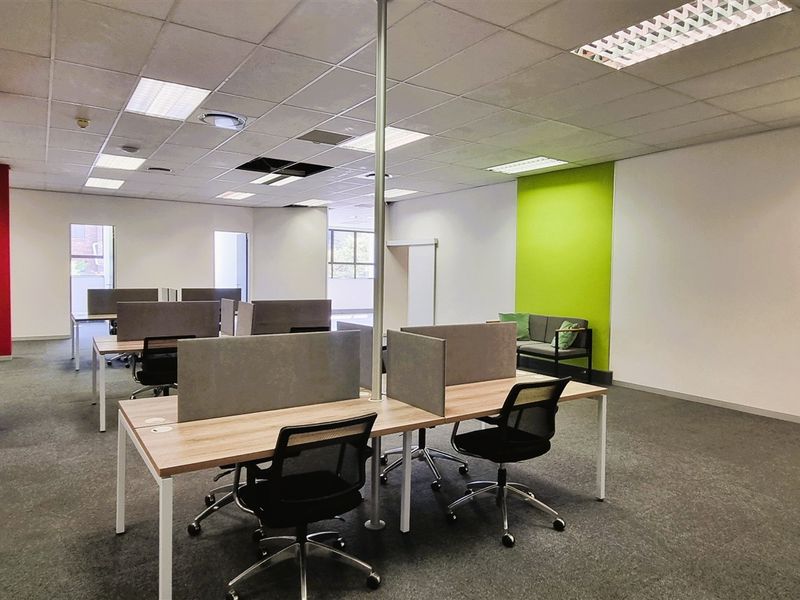 Open-plan office space featuring a suspended ceiling with recessed lighting, carpeted flooring, and a prominent structural column.
