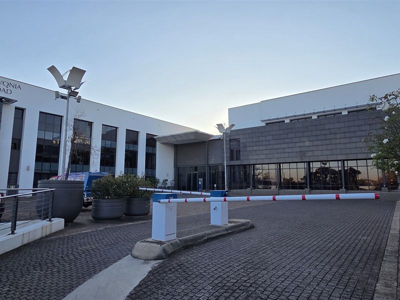 Front exterior view of the office building at 345 Rivonia Road, featuring a paved driveway, security access control, and modern glass facade.