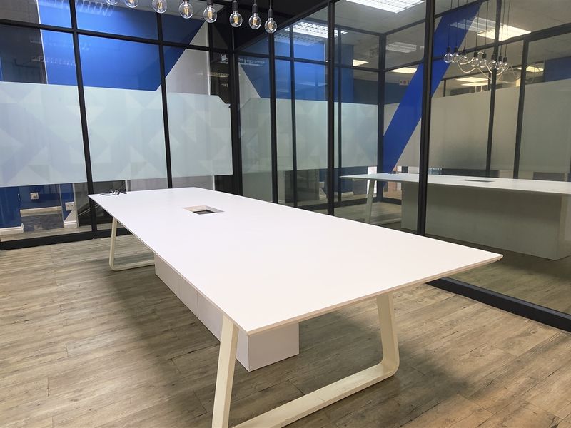 Modern office space featuring glass partition walls, frosted privacy film, and durable laminate flooring, creating a bright and professional work environment.