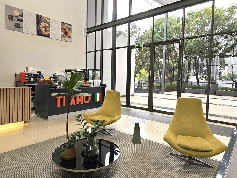 Modern office space featuring a high-ceiling design, floor-to-ceiling glass windows, and a professional built-in service counter area.