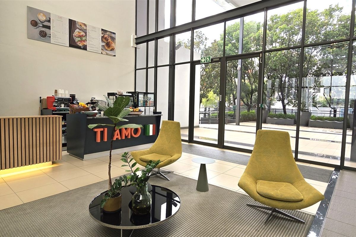 Modern office space featuring a high-ceiling design, floor-to-ceiling glass windows, and a professional built-in service counter area.