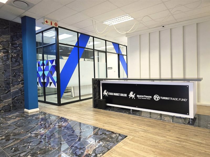 Modern office reception area featuring a branded reception desk, glass-partitioned office spaces, and a combination of marble-effect and wood-look flooring.