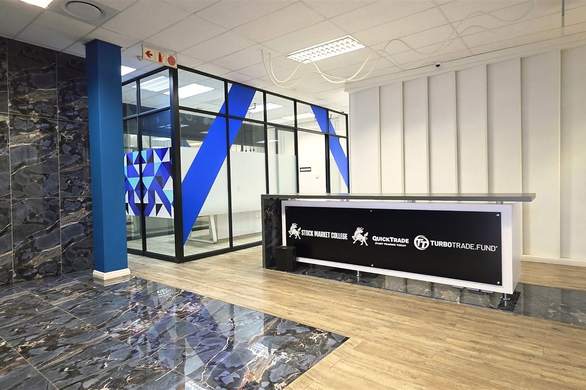 Modern office reception area featuring a branded reception desk, glass-partitioned office spaces, and a combination of marble-effect and wood-look flooring.