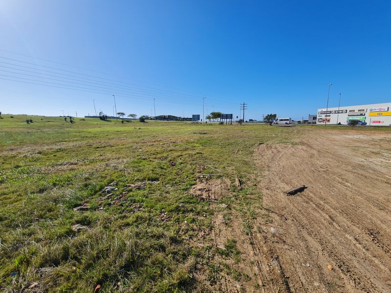 A view of an undeveloped commercial vacant land plot adjacent to an existing retail shopping center.