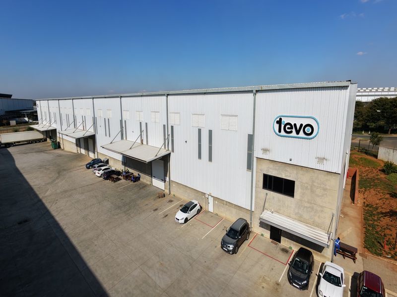 Aerial view of a large industrial warehouse facility featuring multiple loading bays, corrugated metal cladding, and an expansive concrete yard area.