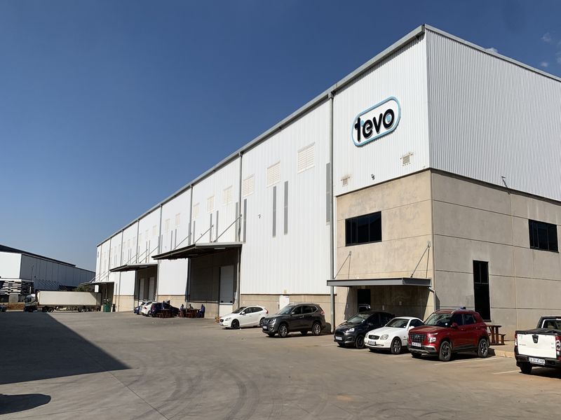 A large industrial warehouse facility featuring corrugated metal cladding, multiple loading bays, and a paved concrete yard area.