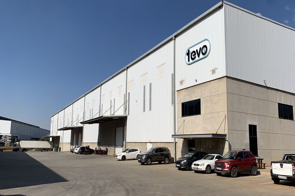 A large industrial warehouse facility featuring corrugated metal cladding, multiple loading bays, and a paved concrete yard area.