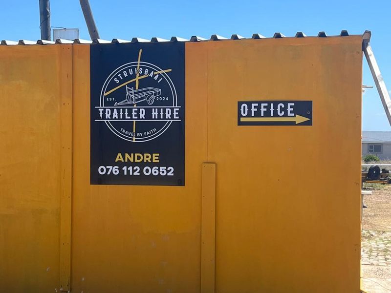 Exterior view of a yellow corrugated metal structure featuring business signage and office directional indicator.