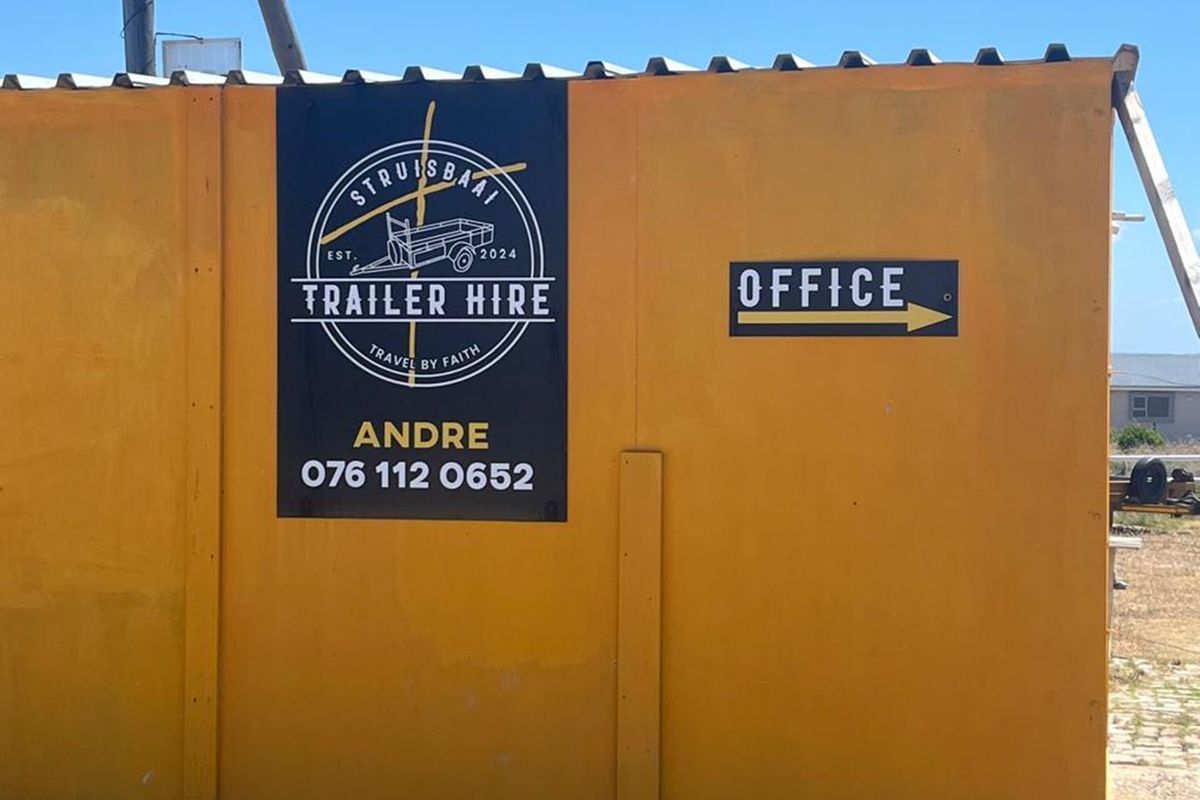 Exterior view of a yellow corrugated metal structure featuring business signage and office directional indicator.