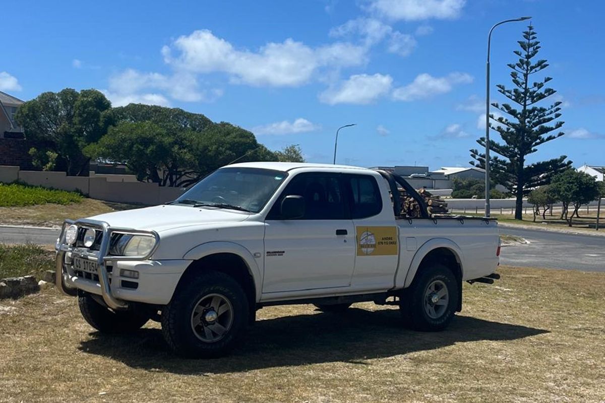 A white pickup truck parked on a dry grass verge in a residential area.