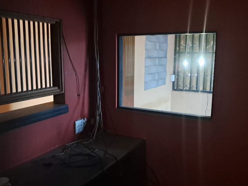 A small, enclosed office or utility space featuring a service window, fixed counter, and dark wall finishes.