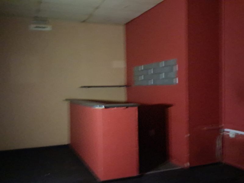 An interior view of a retail space featuring a built-in service counter and red accent walls, suitable for various commercial or retail applications.