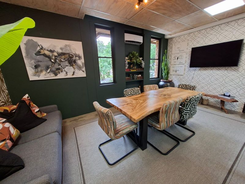 A modern office space featuring a large wooden boardroom table, dark accent walls, built-in shelving, and an integrated air conditioning unit.