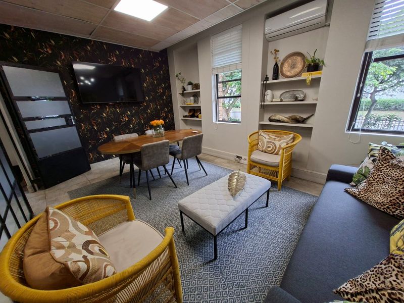 A well-appointed office space featuring built-in shelving, a wall-mounted air conditioning unit, and large windows providing natural light.