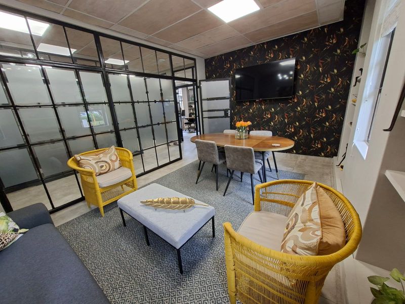 Modern office meeting area featuring industrial-style black metal and glass partitions, patterned feature wallpaper, and recessed ceiling lighting.