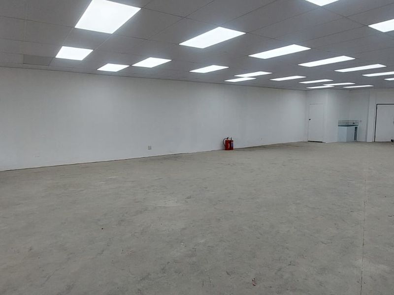 A spacious, open-plan retail unit featuring a suspended ceiling with recessed lighting, large windows, and a neutral, blank-canvas interior ready for custom fit-out.