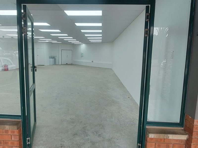 An empty retail space featuring a wide glass entrance, recessed ceiling lighting, and a neutral open-plan layout suitable for various commercial uses.
