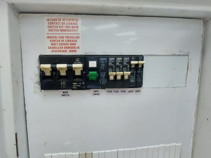 A wall-mounted electrical distribution board featuring a main switch, earth leakage protection, and multiple circuit breakers for lighting and power outlets.
