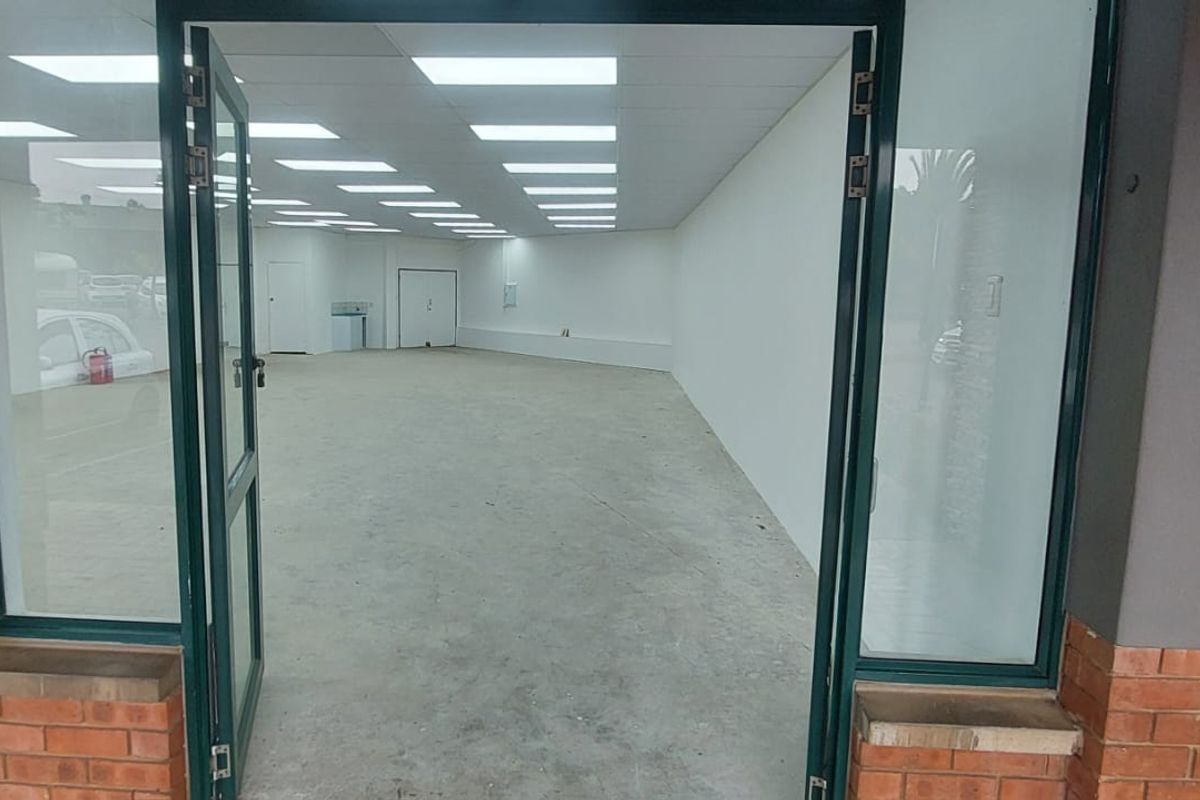 An empty retail space featuring a wide glass entrance, recessed ceiling lighting, and a neutral open-plan layout suitable for various commercial uses.
